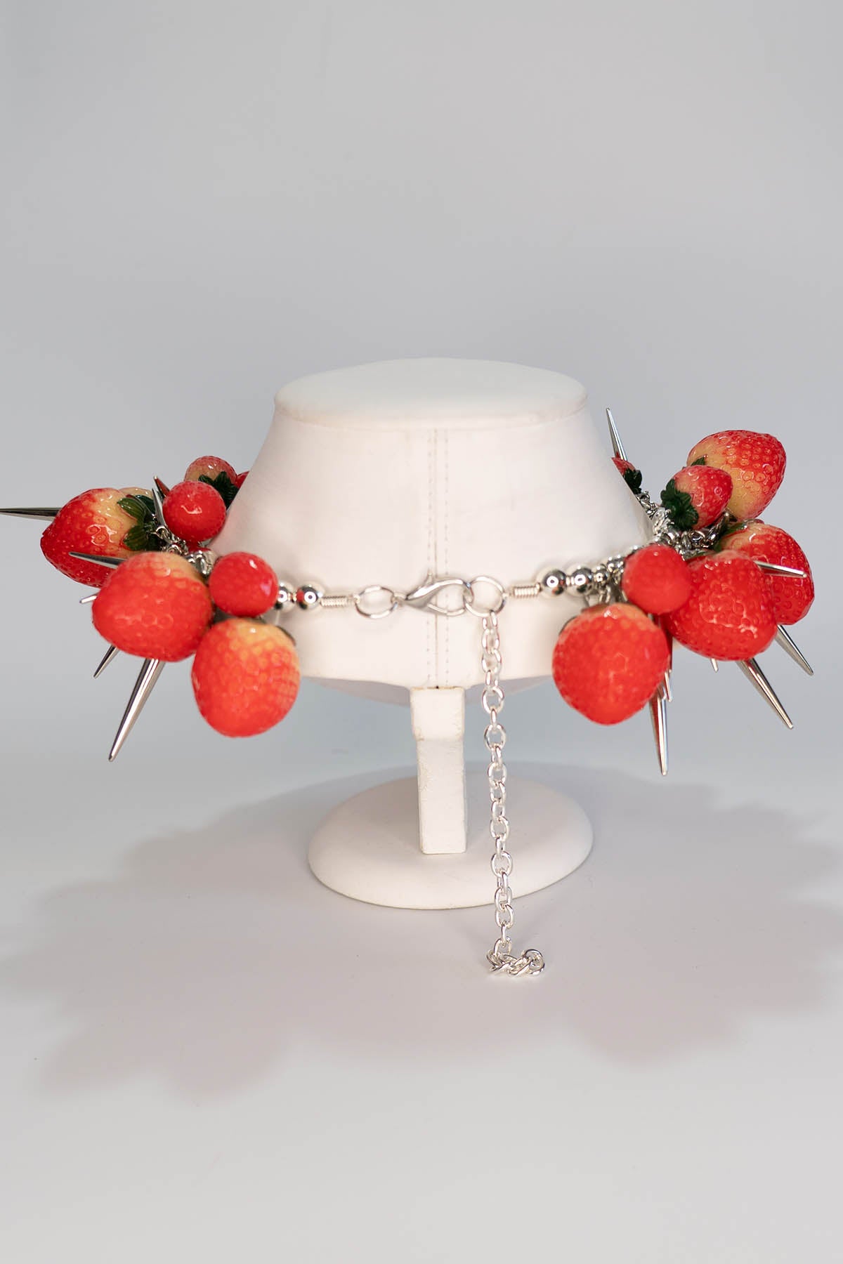 Necklace with strawberry and spike design on a mannequin bust against a gray background