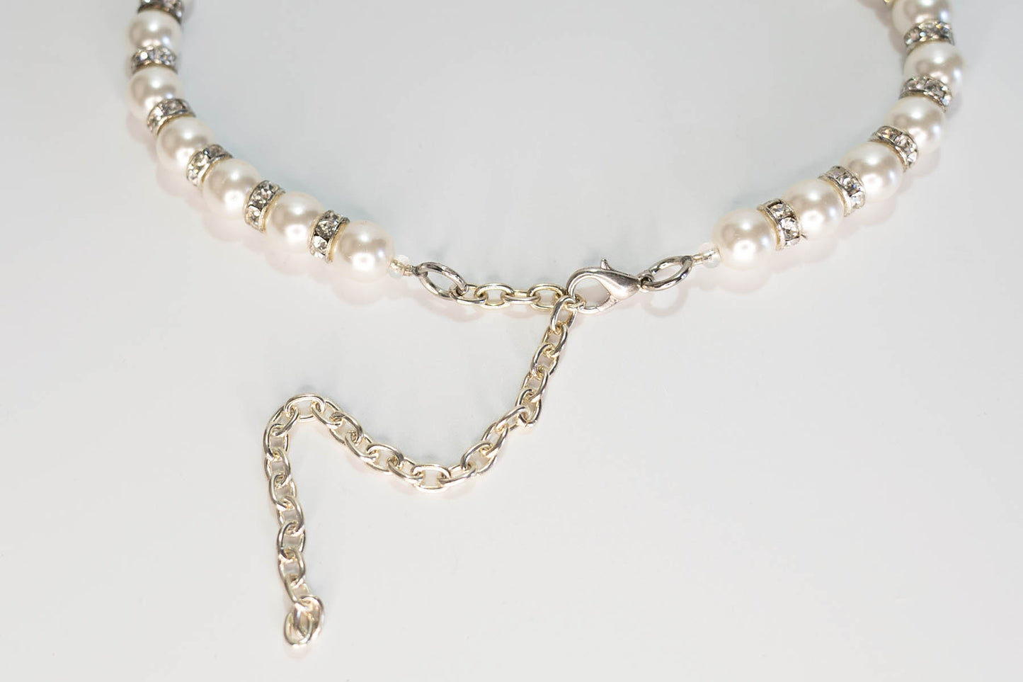 Pearl necklace with a silver chain on a light gray background