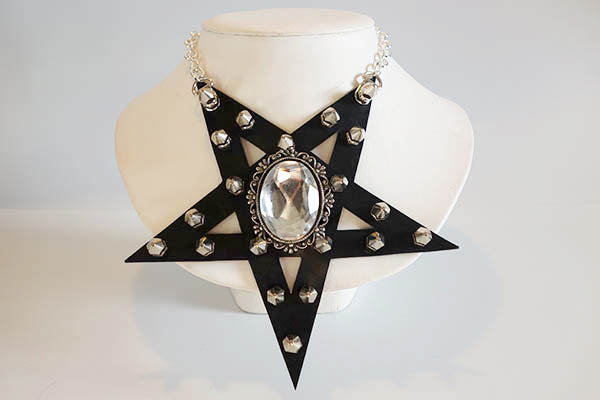 Black star-shaped necklace with silver embellishments on a mannequin bust.