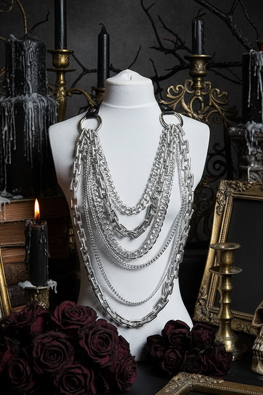Mannequin with layered necklaces against a dark background with candles and skulls