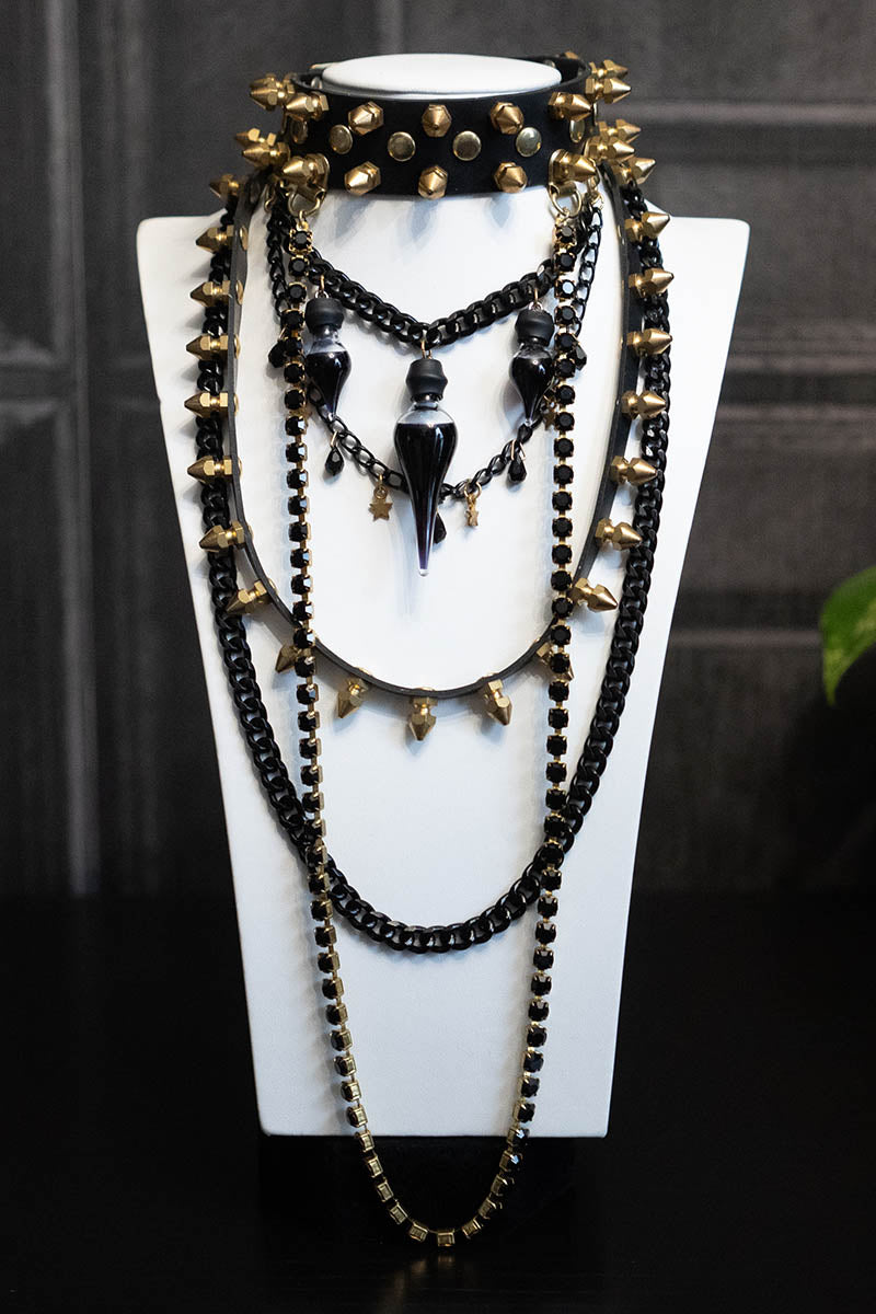 A black choker necklace with gold-colored spikes, diamonds, and Preciosa crystals displayed on a mannequin.