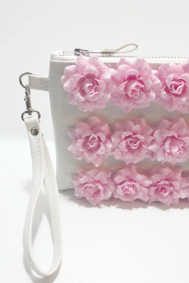 White clutch with pink floral decorations on a white background