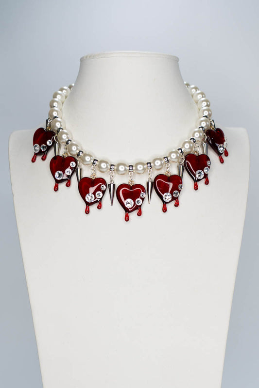 Necklace with red heart-shaped pendants and white pearls on a mannequin.