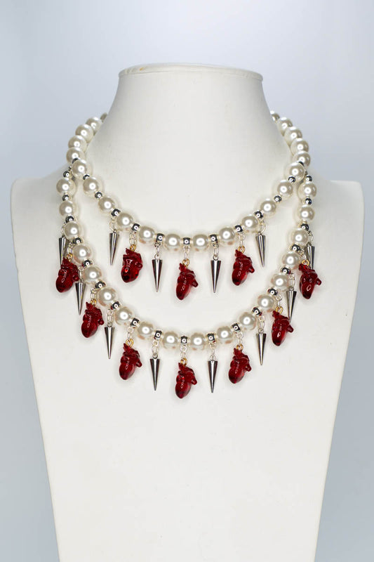 Necklace with red anatomical hearts and spikes on a mannequin bust against a white background