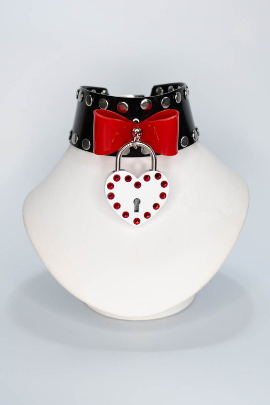 Black choker with red bow and heart-shaped lock on a white mannequin neck against a light gray background