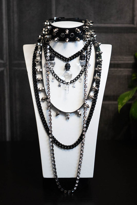 A black layered-style choker necklace with glass bottle-shaped pendants and metallic spikes, displayed on a mannequin.