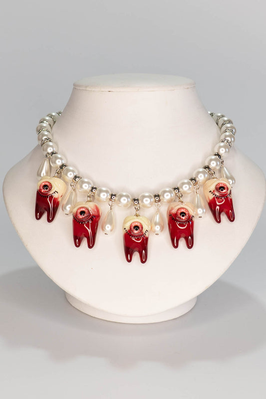 Necklace with red and white tooth beads on a mannequin bust against a gray background