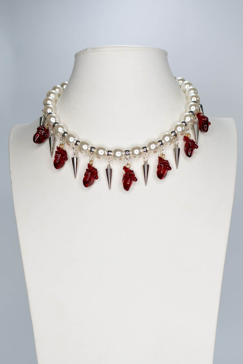 Necklace with red anatomical hearts and spikes on a mannequin bust against a gray background