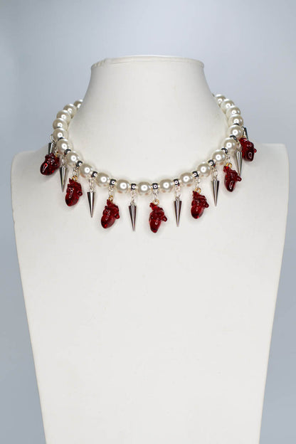Necklace with red anatomical hearts and spikes on a mannequin bust against a gray background