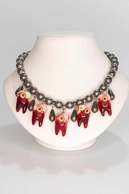 Necklace with red and black pearl beads on a mannequin bust against a gray background