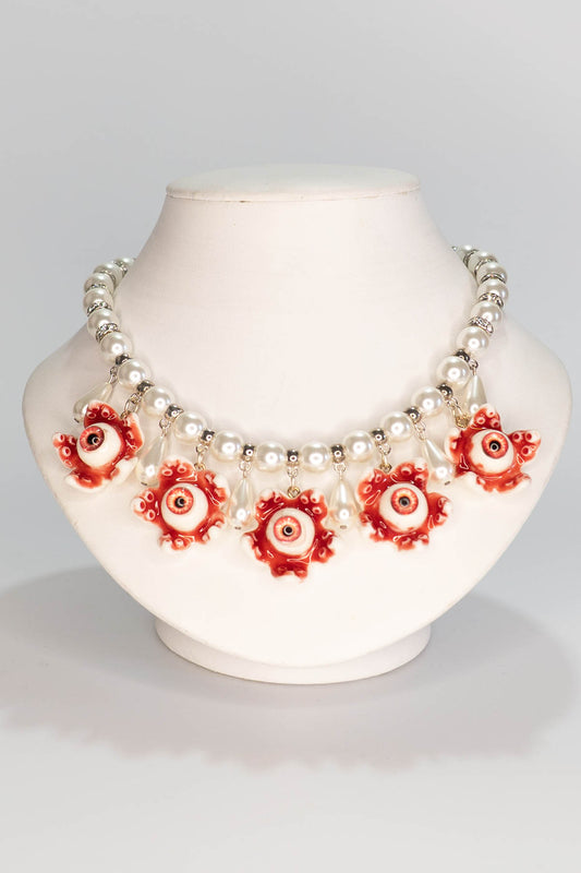 Necklace with red floral eyeball pendants on a mannequin bust against a gray background