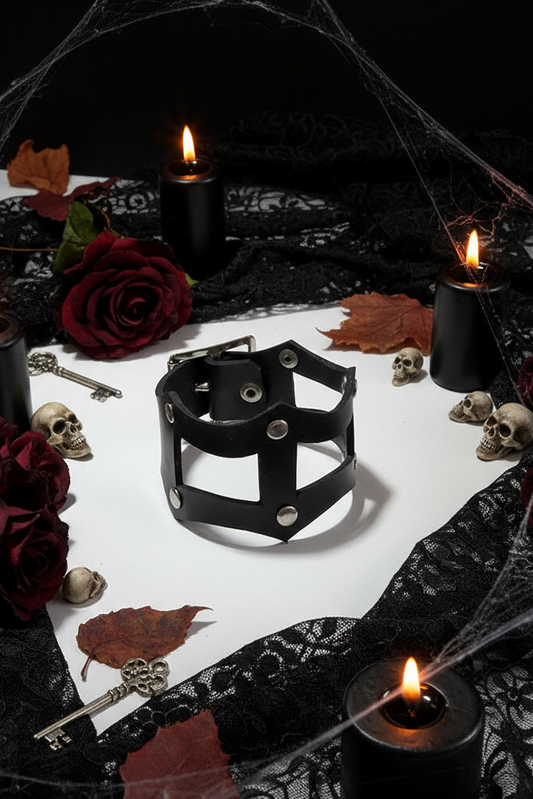 Dark-themed setting with candles, roses, and a small cage bracelet on a white cloth.