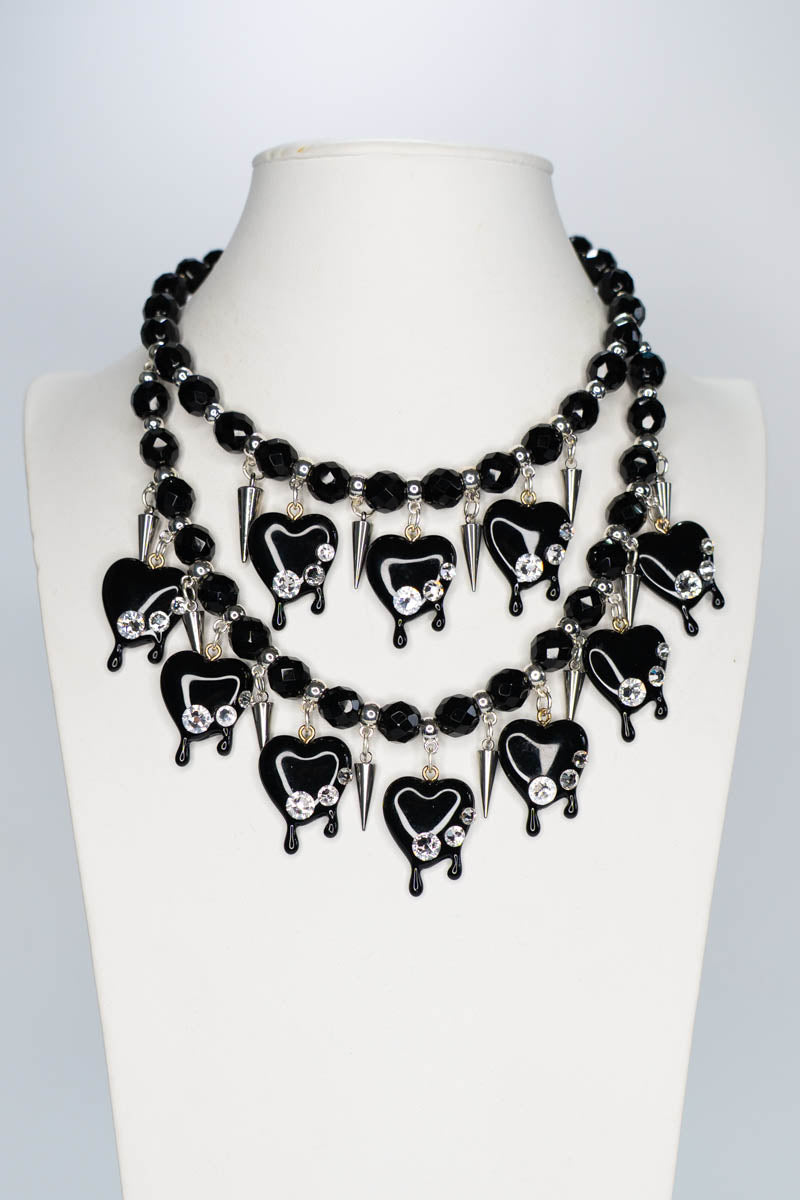 Black beaded necklace with heart-shaped pendants on a mannequin bust against a white background