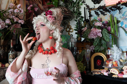 Person in a decorative setting with flowers and candles, eating strawberries.