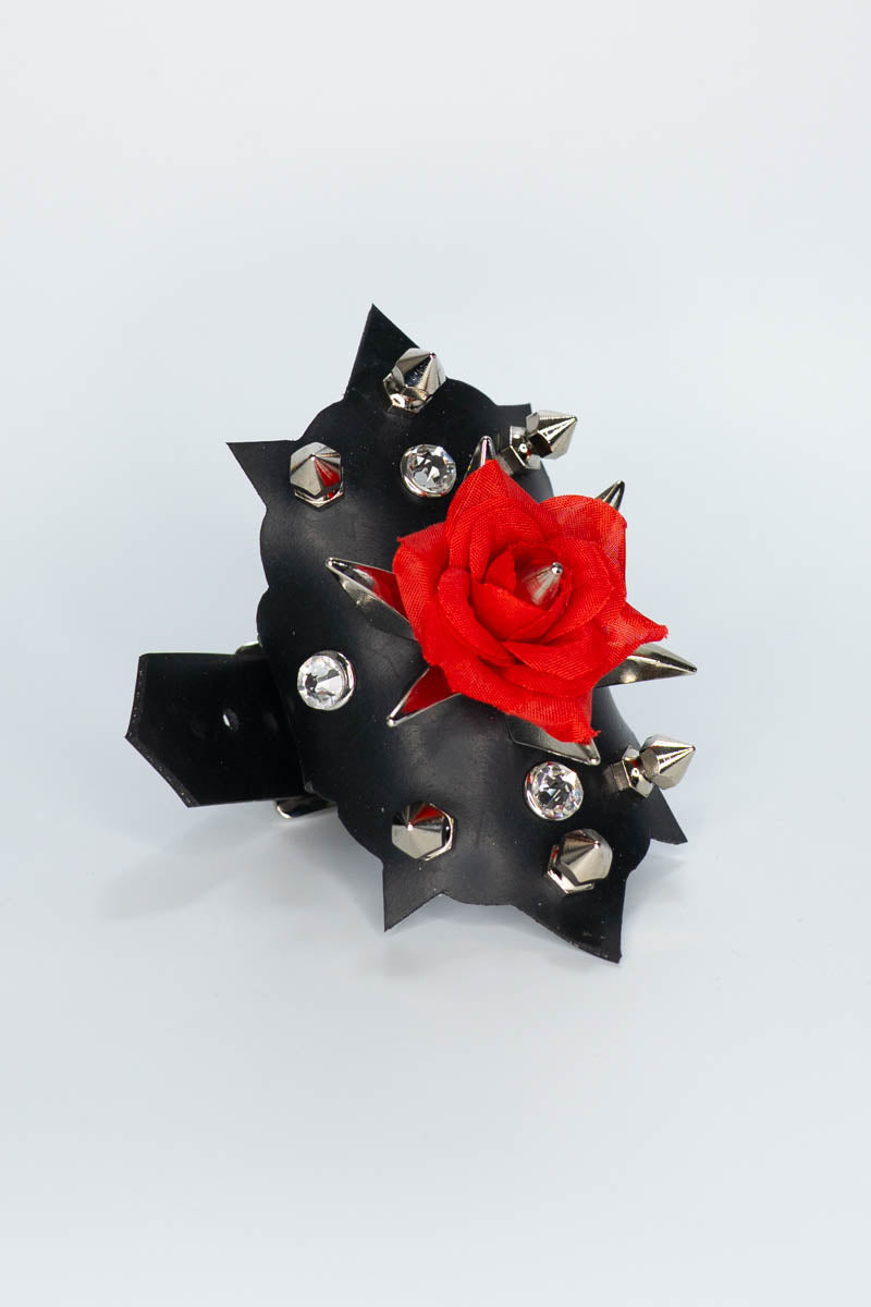 Black rubber bracelet with red rose and spikes on a white background