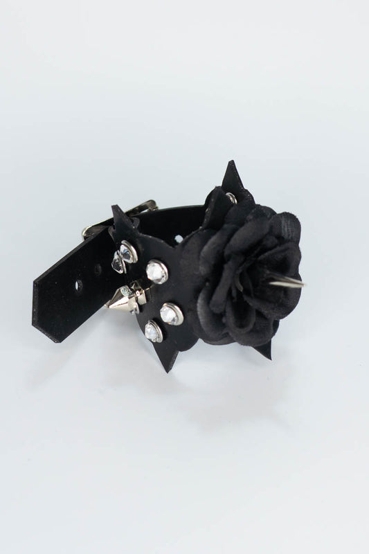 Black rubber bracelet with floral design and silver studs on a white background