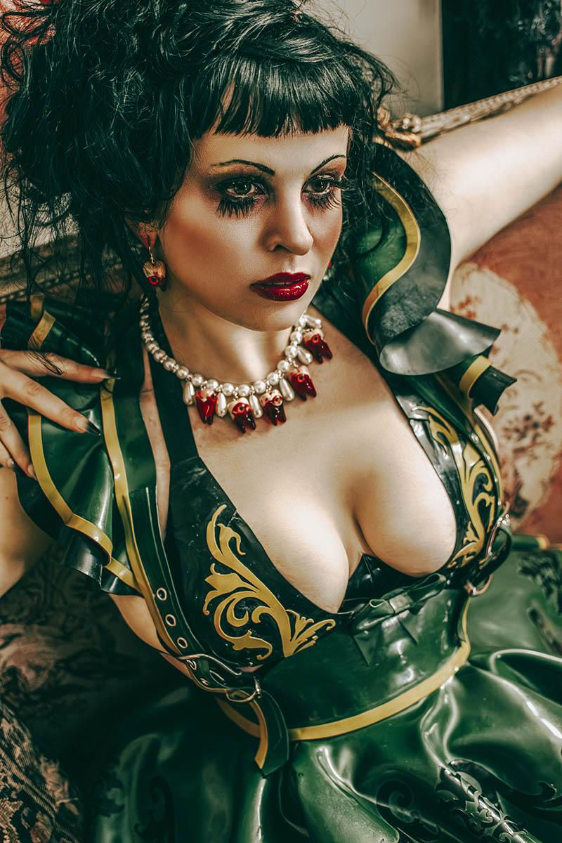 beautiful dark haired girl with striking green costume on a chaise longue