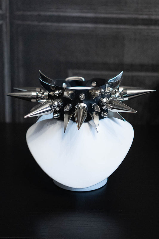 A metal choker necklace with multiple spikes and a shiny, industrial rubber band.