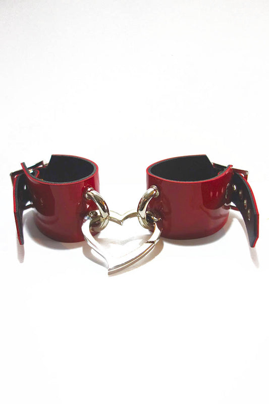 Red leather cuffs with a heart-shaped link on a white background