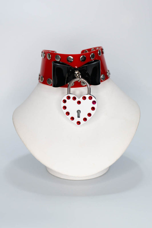 Red pvc choker with a heart-shaped lock on a white stand against a light gray background