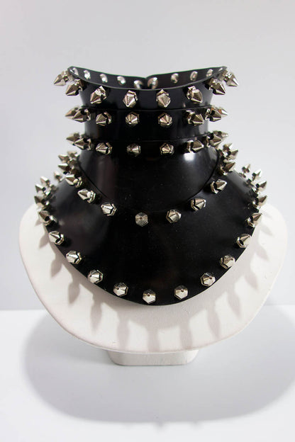 Black studded choker on a white stand against a light gray background