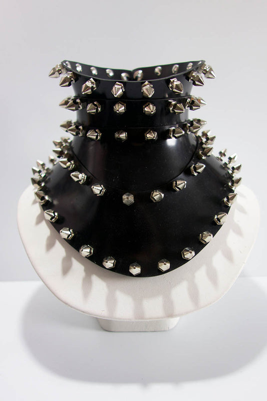 Black studded choker on a white stand against a light gray background