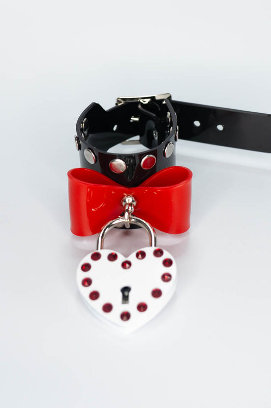 Black pvc bracelet with red bow and heart-shaped lock on a white background