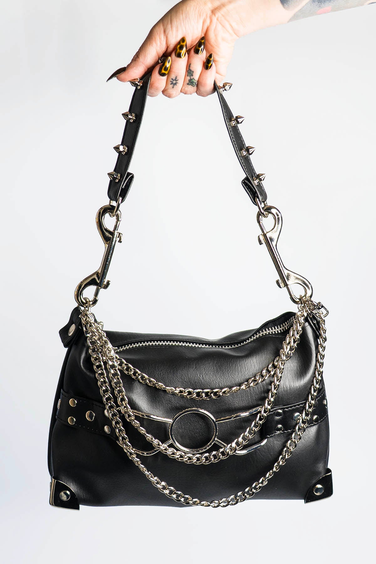 Black handbag with chain details held by a hand on a white background