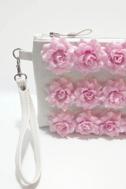White clutch with pink floral decorations on a white background