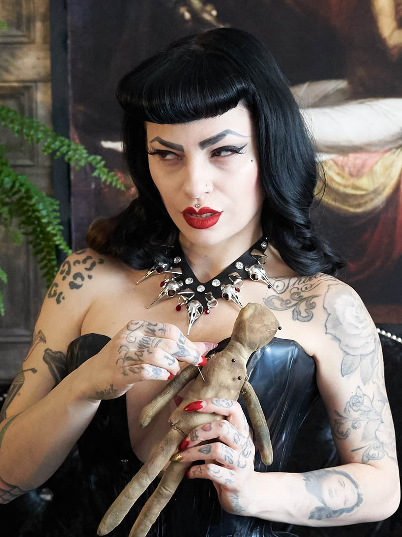 dark haired pip up model looks devilish with a voodoo doll, casting her curse o the one who did her wrong
